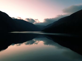 Scenic view of lake and mountains against sky during sunset