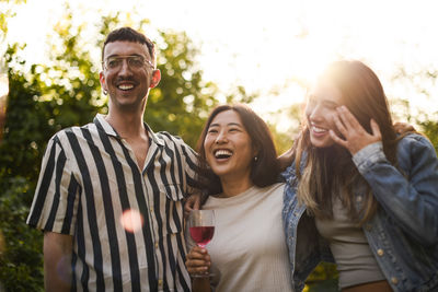 Portrait of smiling friends standing against trees