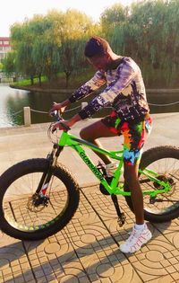 Young man riding bicycle by water