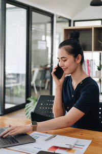 Businesswoman talking on phone while working at office