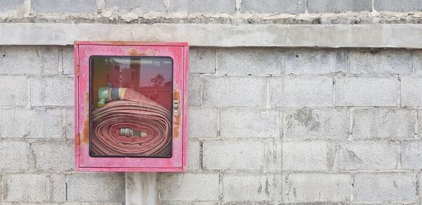 Fire hose rack with hose reel inside hang on concrete block wall