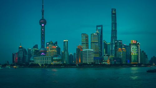 Illuminated modern buildings in city against sky