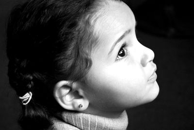 Close-up of girl looking away against black background