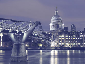 Bridge over river against sky in illuminated city at night