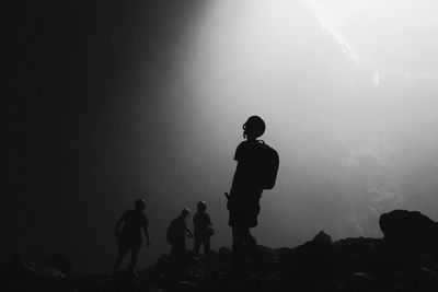 Silhouette men standing in cave
