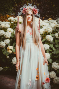 Beautiful young woman standing by flowering plants