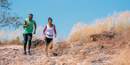 Full length of couple running on land against sky