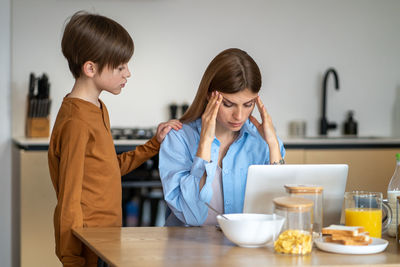 Side view of young woman using mobile phone at home