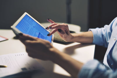 Cropped image of businesswoman using tablet computer while sitting at desk