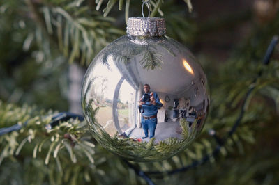 Man photographing while reflecting on christmas bauble