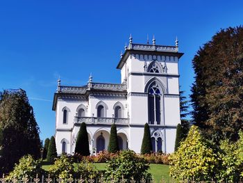 Low angle view of building and trees against blue sky