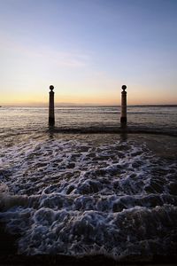 Lighthouse by sea against sky during sunset