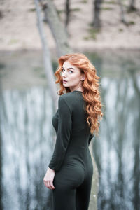 Portrait of young woman standing against trees