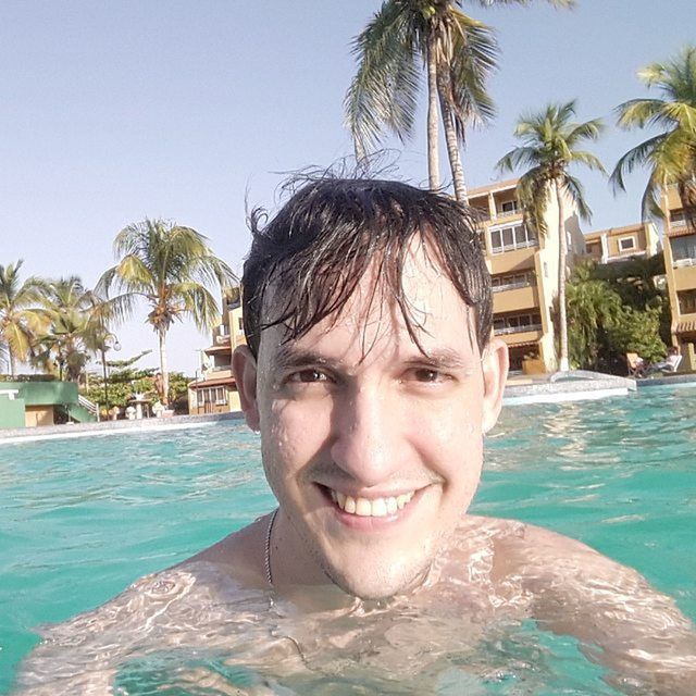 water, swimming pool, palm tree, person, blue, sea, leisure activity, tree, lifestyles, portrait, looking at camera, beach, young adult, sunlight, headshot, day, clear sky, waterfront