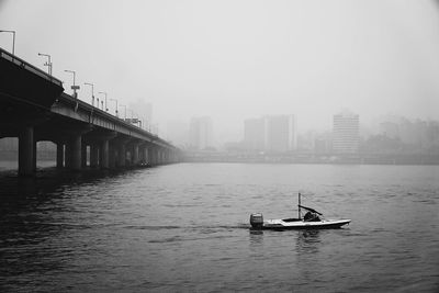 Boat in river against sky during foggy weather