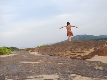 Rear view of woman standing on rock