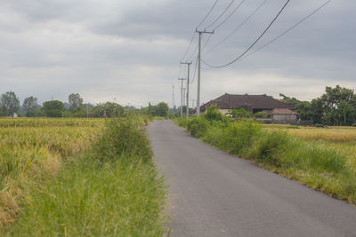 Road amidst field against sky