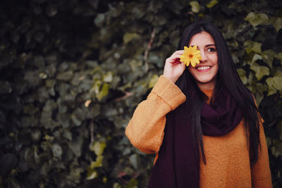 Portrait of young woman standing against plants