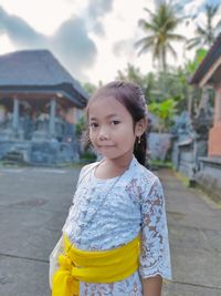 Portrait of young woman standing against trees