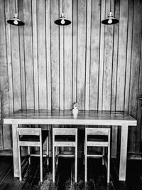 Empty chairs and table against wall in restaurant