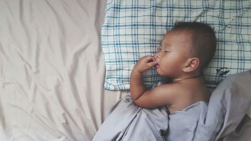 High angle view of shirtless baby boy sleeping on bed at home