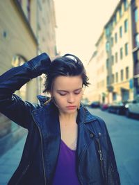 Beautiful young woman looking down with buildings in background