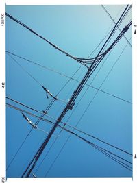 Low angle view of electricity pylon against blue sky