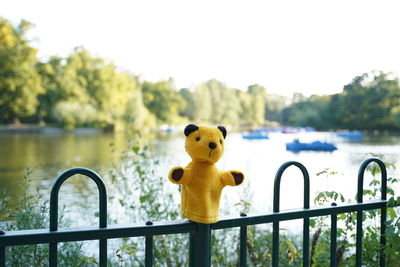 Close-up of stuffed toy on railing against lake