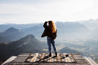 Rear view of woman standing on mountain against sky