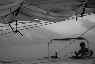 Man steering yacht against sky at dusk