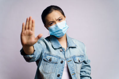 Portrait of young woman standing gesturing against gray background