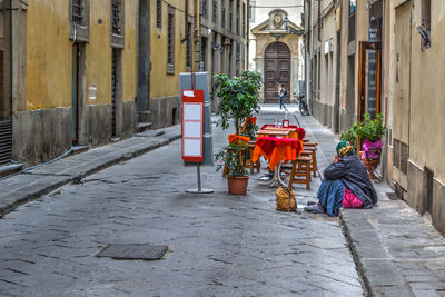 Rear view of men sitting on street amidst buildings in city