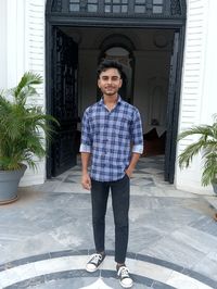 Portrait of smiling young man standing against building