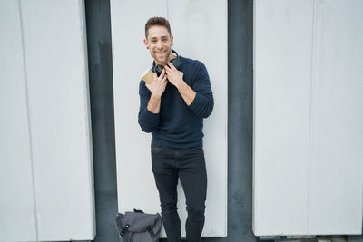 Modern man in casual clothes near a white wall with headphones and cof