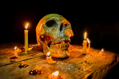 Close-up of lit candles around human skull on table