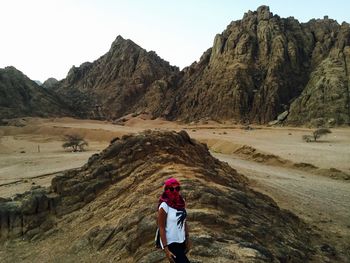 Rear view of woman walking on mountain against sky