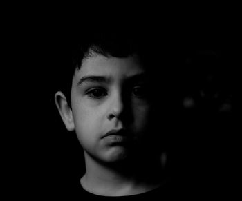 Close-up portrait of boy against black background