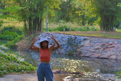 Woman standing by stream in forest