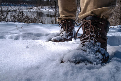 Low section of man wearing shoes standing on snow covered field