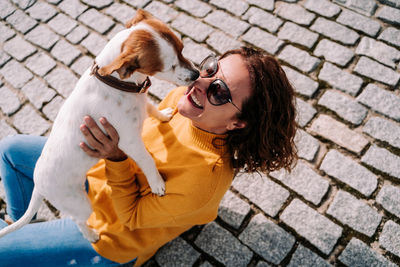 High angle view of woman embracing with dog sitting street
