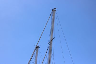 Low angle view of cranes against clear blue sky