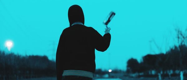 Rear view of silhouette man standing against sky