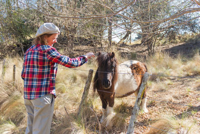 Woman standing with horse in farm