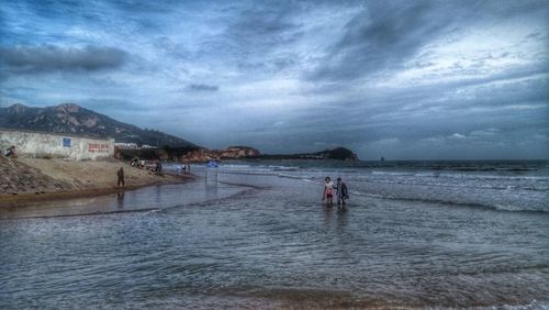 Scenic view of calm beach against cloudy sky