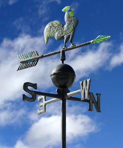 Low angle view of weather vane against blue sky