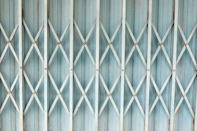 Full frame shot of metal fence against wall