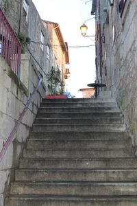 Low angle view of staircase amidst buildings against sky