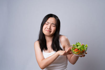 Young woman holding ice cream against white background