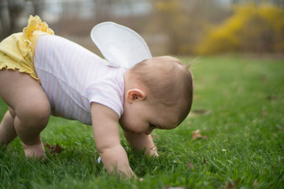 Baby girl lying on grassy field