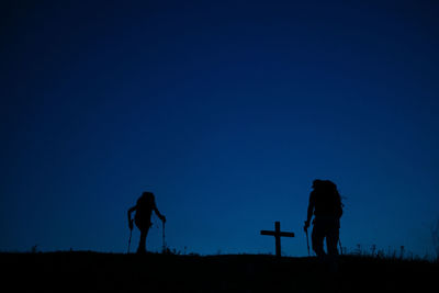 Silhouette people standing on field against clear blue sky